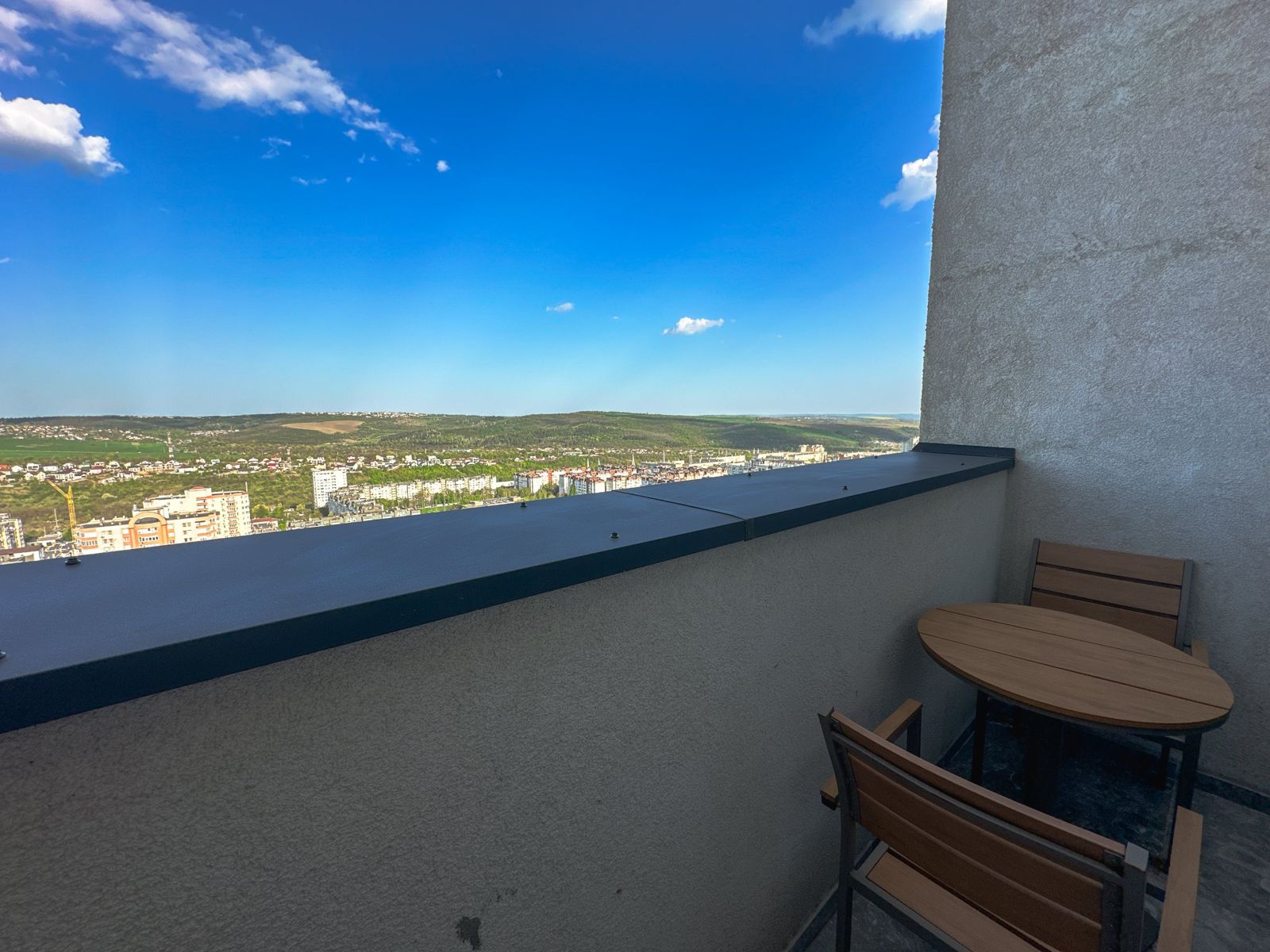 Balcony table and chairs with a wide view over Chișinău and the green hills beyond